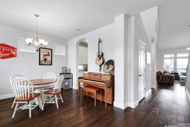 dining room with dark wood finished floors, visible vents, baseboards, and arched walkways
