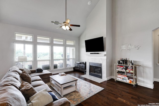 living area featuring high vaulted ceiling, dark wood-type flooring, ceiling fan, baseboards, and a tile fireplace