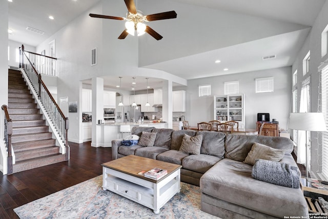 living area featuring high vaulted ceiling, visible vents, a ceiling fan, and dark wood-style floors