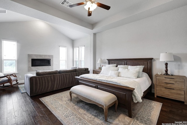 bedroom featuring dark wood finished floors, visible vents, baseboards, a glass covered fireplace, and vaulted ceiling