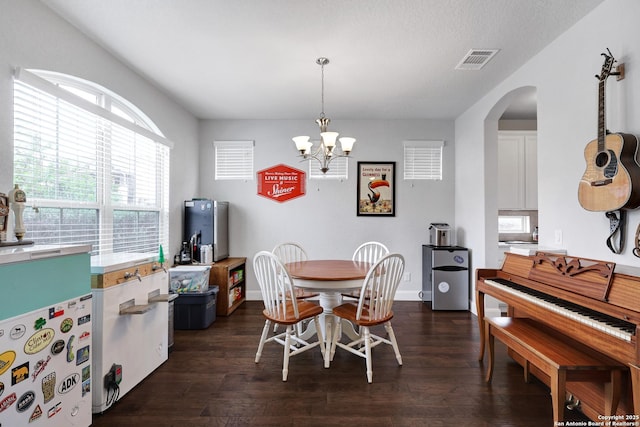 dining space with a notable chandelier, baseboards, dark wood-style flooring, visible vents, and arched walkways