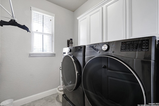 washroom featuring washing machine and clothes dryer, cabinet space, and baseboards