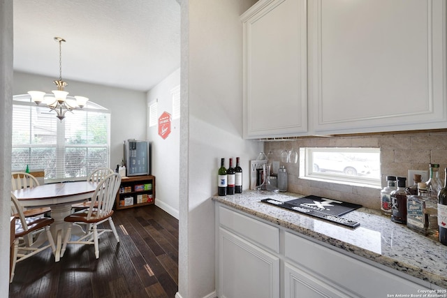 kitchen featuring light stone countertops, a chandelier, backsplash, white cabinets, and dark wood-style floors