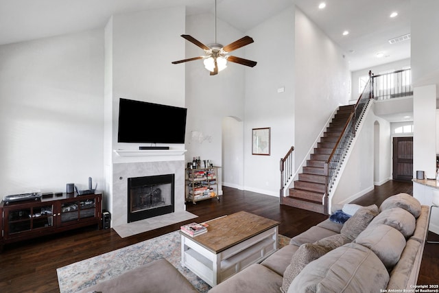 living area with arched walkways, ceiling fan, stairway, and high vaulted ceiling