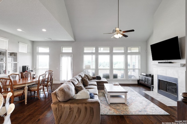 living room featuring a tile fireplace, plenty of natural light, dark wood finished floors, and ceiling fan