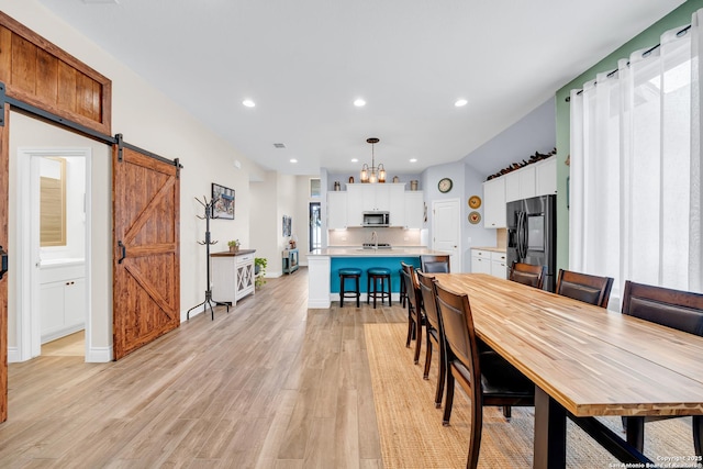 dining area featuring recessed lighting, a barn door, baseboards, an inviting chandelier, and light wood-style floors