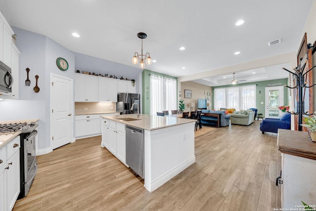 kitchen featuring light wood-style flooring, a sink, stainless steel appliances, open floor plan, and visible vents