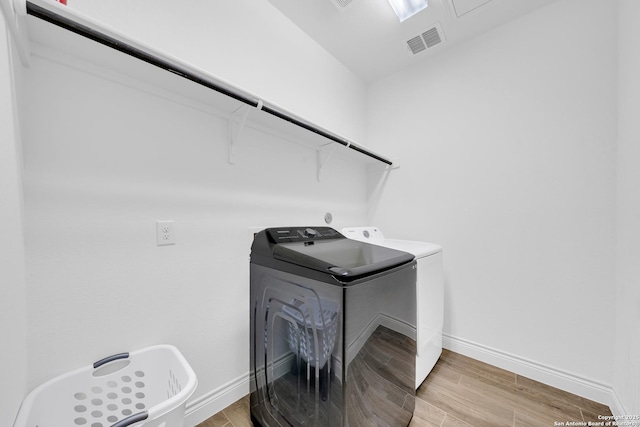 laundry area with laundry area, visible vents, washer and dryer, baseboards, and light wood-style floors