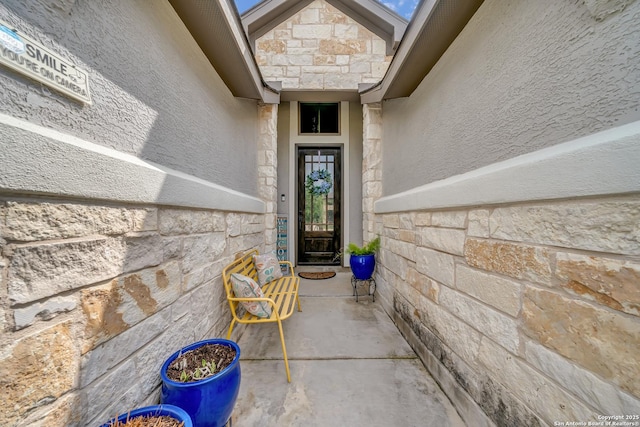 view of exterior entry with stone siding and stucco siding