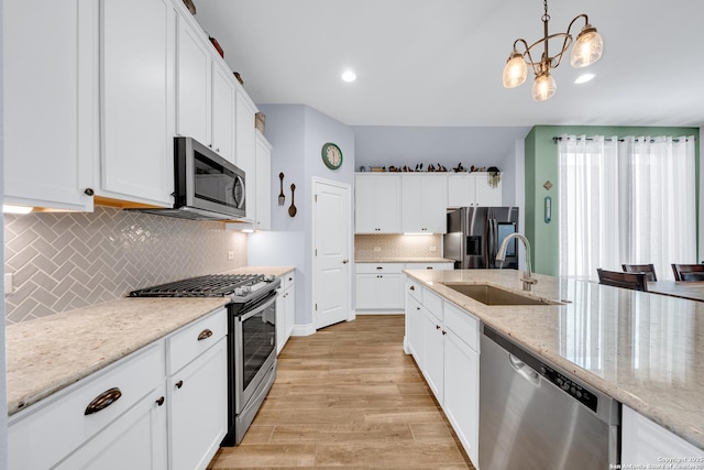 kitchen featuring a sink, appliances with stainless steel finishes, decorative backsplash, white cabinets, and light wood-style floors
