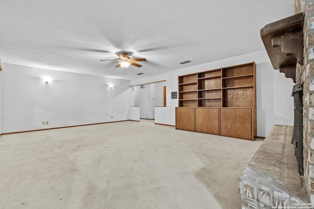 616 Ridgecrest, New Braunfels, TX 78130 - unfurnished living room featuring light colored carpet, a textured ceiling, visible vents, ceiling fan, and a brick fireplace