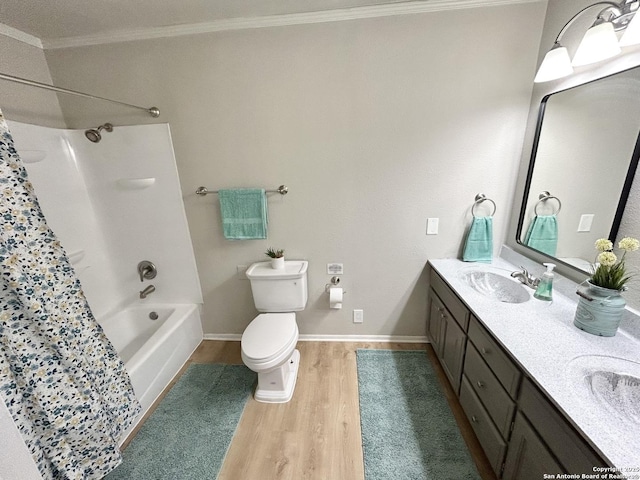 bathroom featuring double vanity, toilet, wood finished floors, a sink, and crown molding