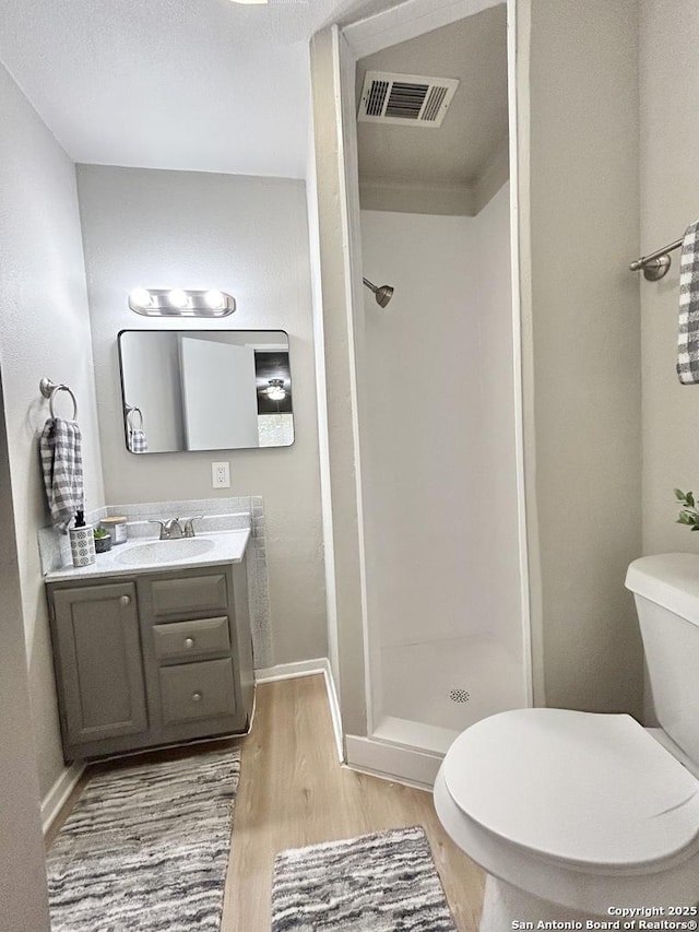 bathroom with toilet, visible vents, a shower stall, vanity, and wood finished floors