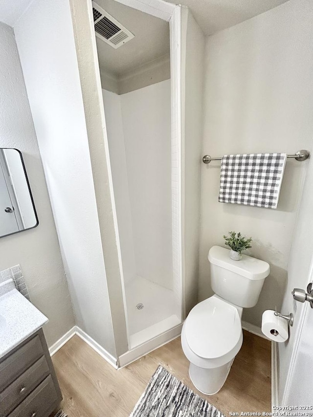 full bathroom featuring toilet, visible vents, wood finished floors, and a stall shower