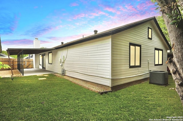 property exterior at dusk with cooling unit, a patio, fence, and a yard
