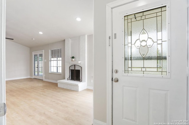 entrance foyer featuring light wood-type flooring, baseboards, a brick fireplace, and recessed lighting