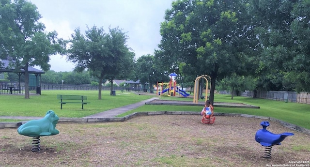 view of home's community featuring fence, playground community, and a lawn