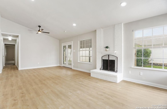 unfurnished living room with a ceiling fan, baseboards, vaulted ceiling, a fireplace, and light wood-type flooring