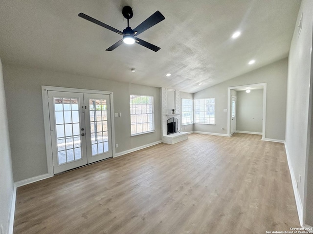 unfurnished living room featuring vaulted ceiling, ceiling fan, french doors, and light wood-style floors