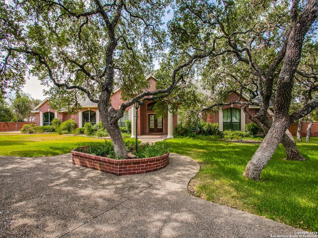 244 Mecca, Hollywood Park, TX 78232 - view of property hidden behind natural elements featuring a front lawn, french doors, and brick siding