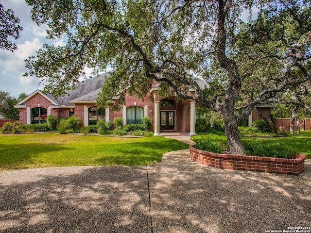 view of front of house featuring french doors, brick siding, and a front lawn