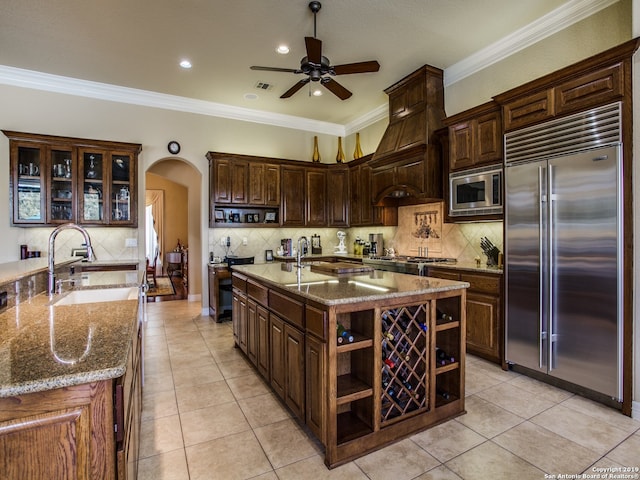 kitchen with a ceiling fan, a sink, open shelves, built in appliances, and arched walkways