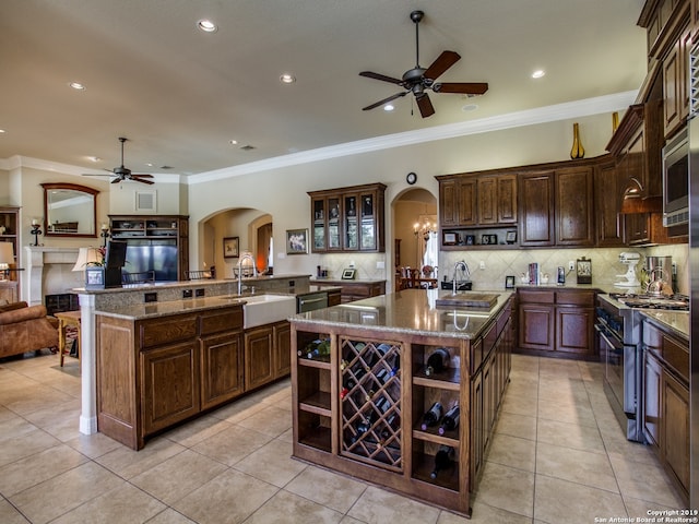 kitchen with a sink, open shelves, ceiling fan, arched walkways, and appliances with stainless steel finishes