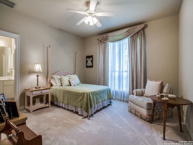 bedroom featuring light colored carpet, ensuite bath, visible vents, a ceiling fan, and baseboards