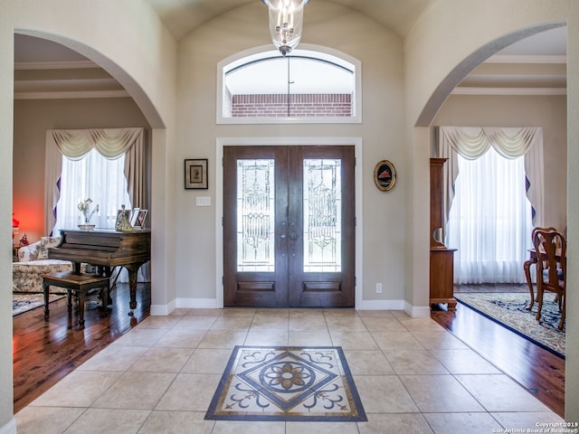 tiled entrance foyer with baseboards, french doors, plenty of natural light, and arched walkways