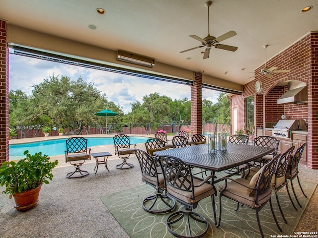 view of patio / terrace with fence, exterior kitchen, a community pool, ceiling fan, and grilling area