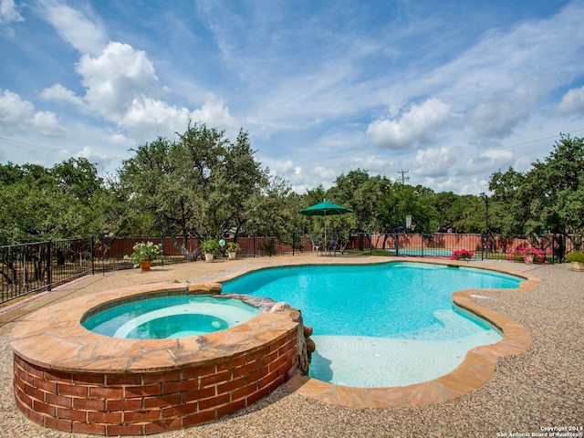 view of swimming pool featuring a pool with connected hot tub and a fenced backyard
