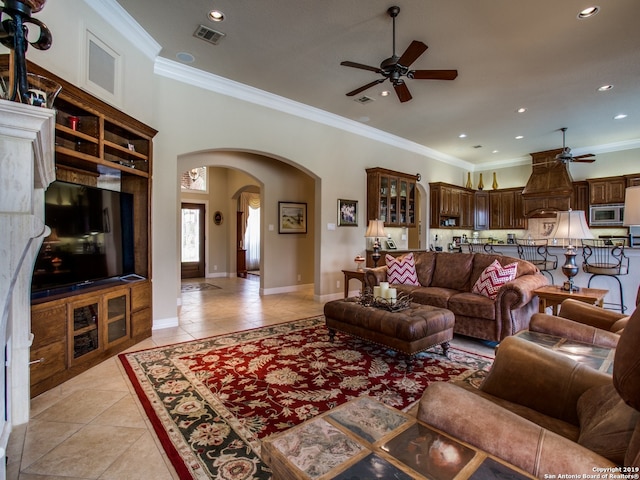 living area featuring a ceiling fan, light tile patterned floors, visible vents, and arched walkways