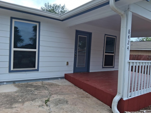 view of exterior entry with a patio area and a wooden deck
