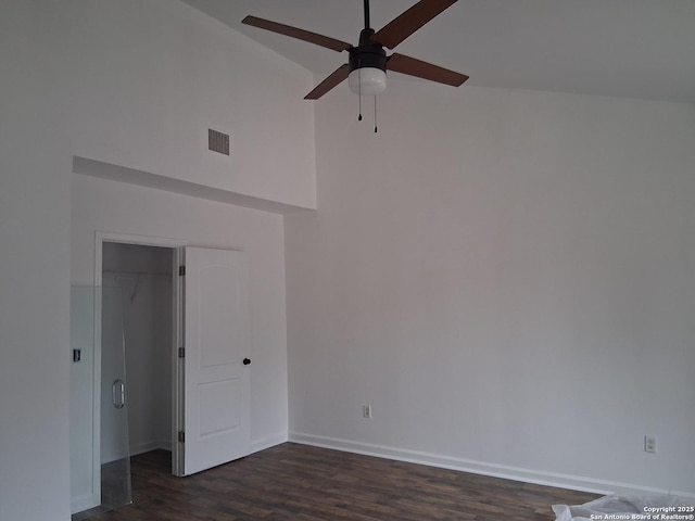 unfurnished room with baseboards, dark wood finished floors, ceiling fan, visible vents, and a towering ceiling