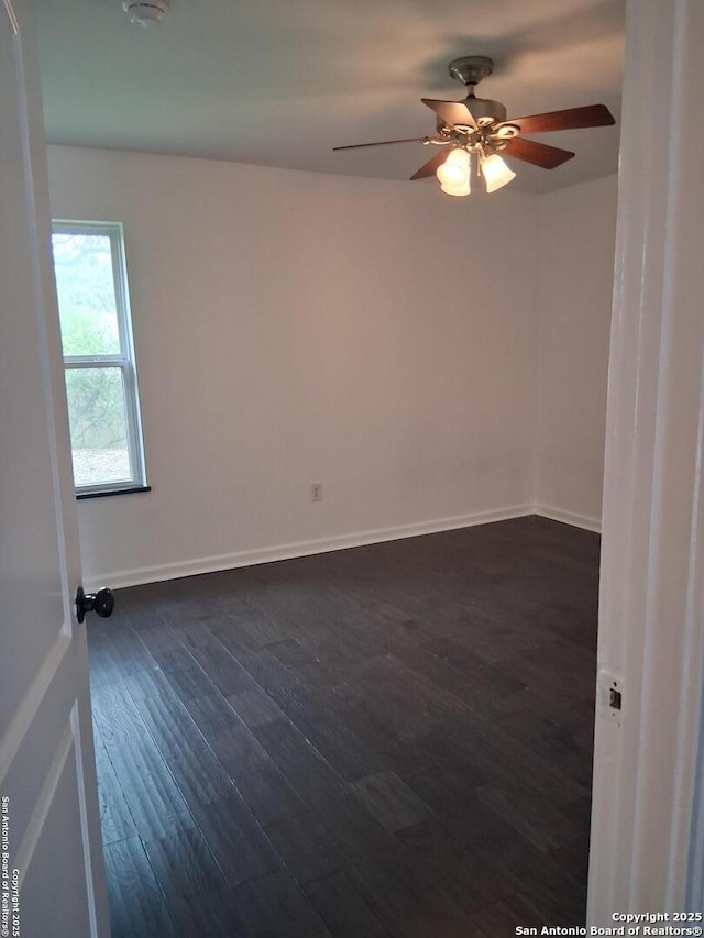 spare room with baseboards, a ceiling fan, and dark wood finished floors