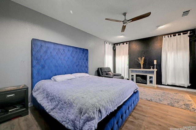 bedroom featuring a ceiling fan, visible vents, and wood finished floors
