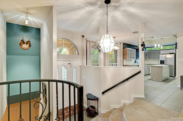 staircase with a chandelier, a healthy amount of sunlight, and tile patterned floors