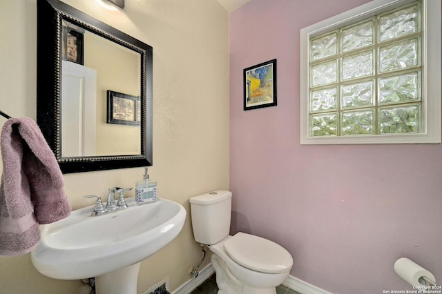 half bath with a sink, toilet, and baseboards
