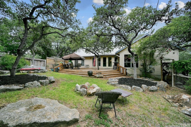back of house featuring a lawn, a deck, french doors, and fence