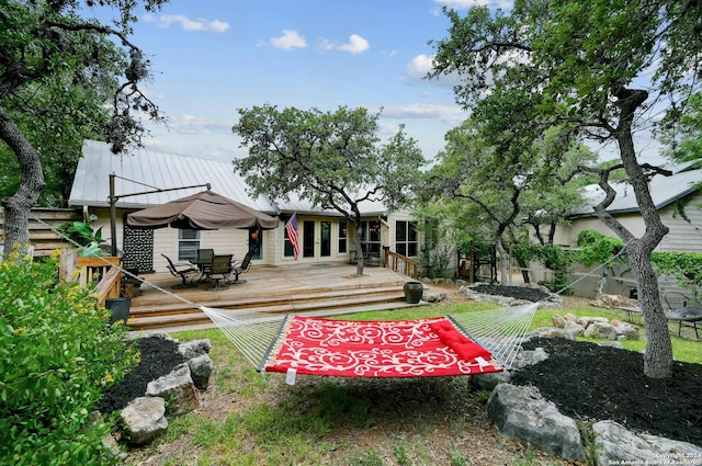 back of property featuring metal roof, a wooden deck, and a standing seam roof