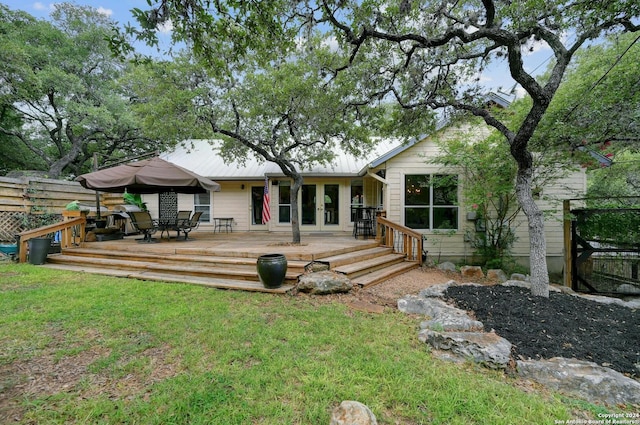 back of house featuring french doors, fence, a lawn, metal roof, and a deck