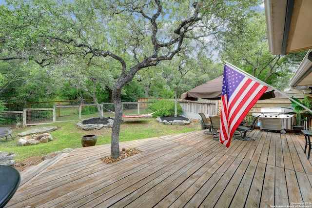 wooden deck with a yard, grilling area, outdoor dining area, and a fenced backyard