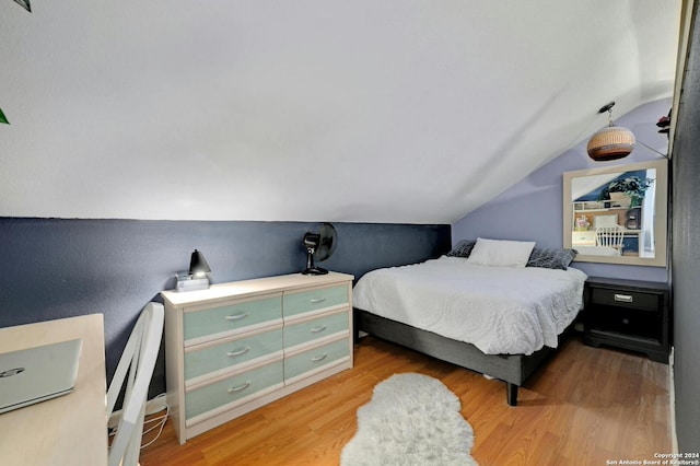 bedroom with vaulted ceiling and wood finished floors