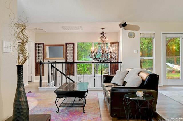 living room featuring a notable chandelier, a healthy amount of sunlight, visible vents, and wood finished floors