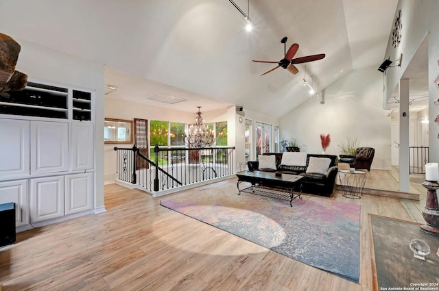 living area with ceiling fan with notable chandelier, high vaulted ceiling, light wood-type flooring, track lighting, and baseboards