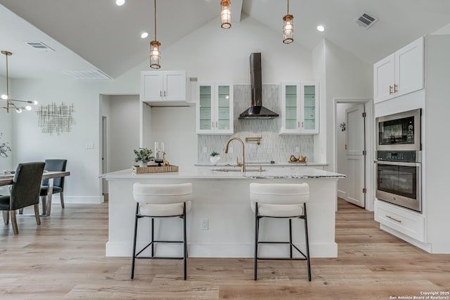 109 Hidden Hls, Floresville, TX 78114 - kitchen featuring built in microwave, a kitchen bar, oven, visible vents, and wall chimney range hood