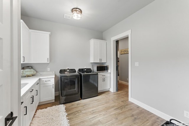 821 Bingham Ln, New Braunfels, TX 78132 - laundry room with baseboards, light wood finished floors, independent washer and dryer, and cabinet space