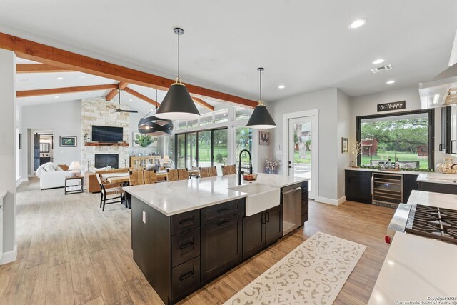 821 Bingham Ln, New Braunfels, TX 78132 - kitchen featuring a sink, lofted ceiling with beams, visible vents, a fireplace, and beverage cooler