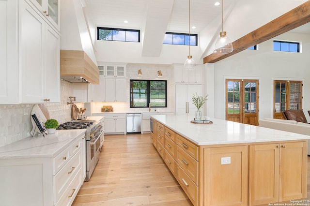 kitchen with light wood-style flooring, a healthy amount of sunlight, premium range hood, decorative backsplash, and appliances with stainless steel finishes