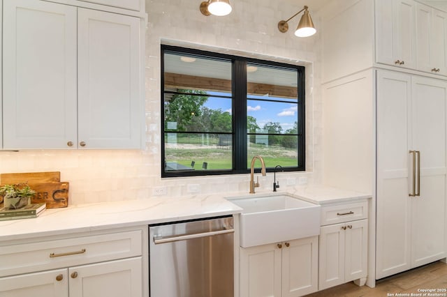 kitchen with a sink, light stone counters, dishwasher, white cabinetry, and decorative backsplash